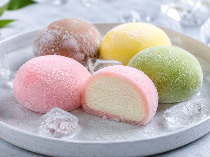 Japońskie mochi z lodami — zimny deser z miękkiego ciasta ryżowego Domowe mochi z lodami o różnych smakach, różowe, zielone i białe kulki na talerzu z lodem